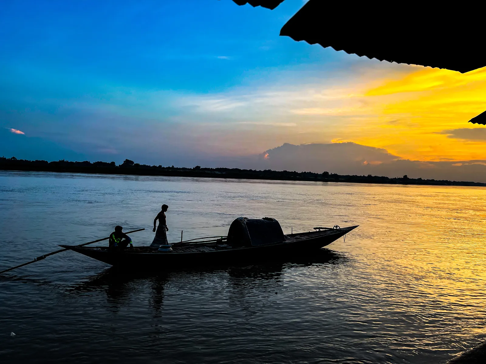Homeward: A boat crosses the river as the clouds turn orange.